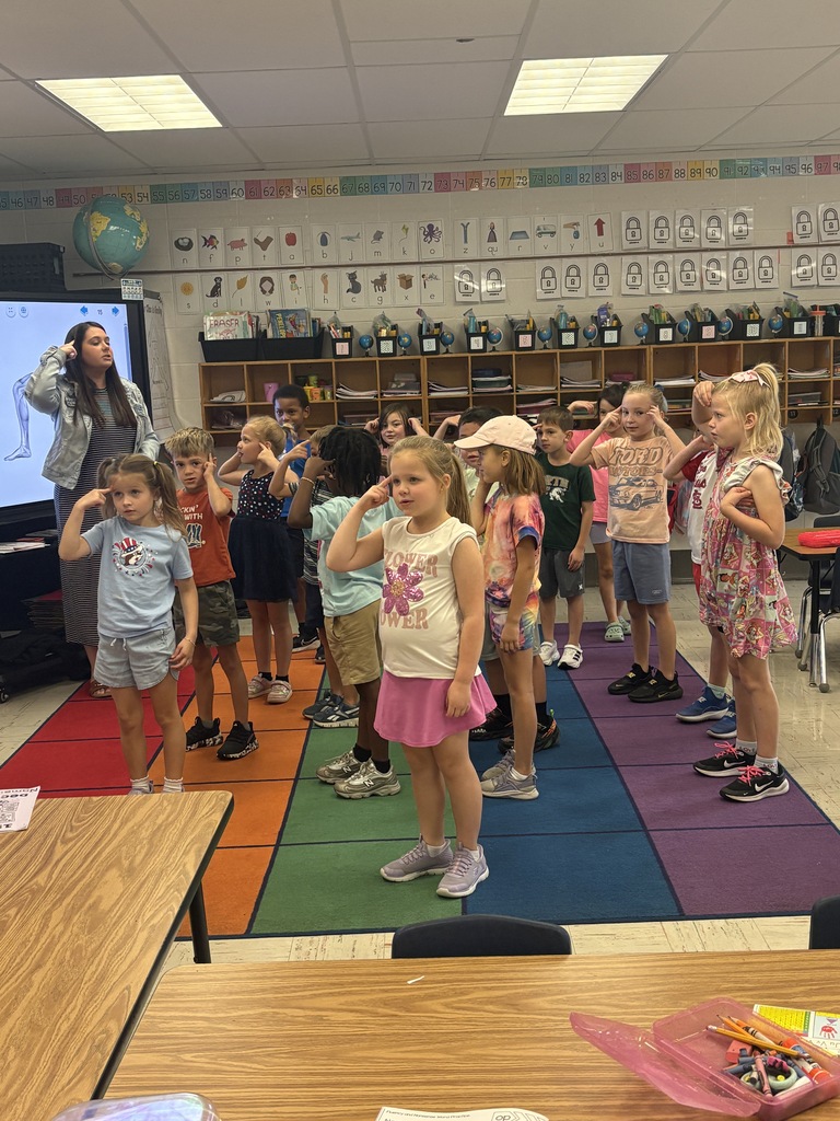 Students following what their teacher is doing and pointing to their heads.