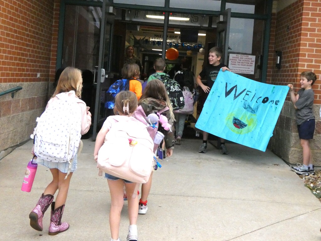 Students hold giant welcome sign for peers as they enter school