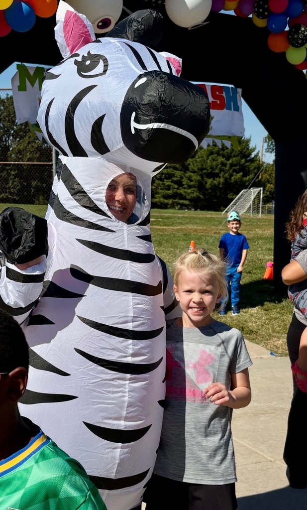 Adults helping students outside during a race. Everyone is dressed in costumes.