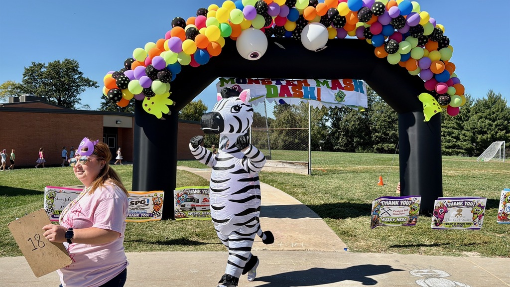 Adults helping students outside during a race. Everyone is dressed in costumes.