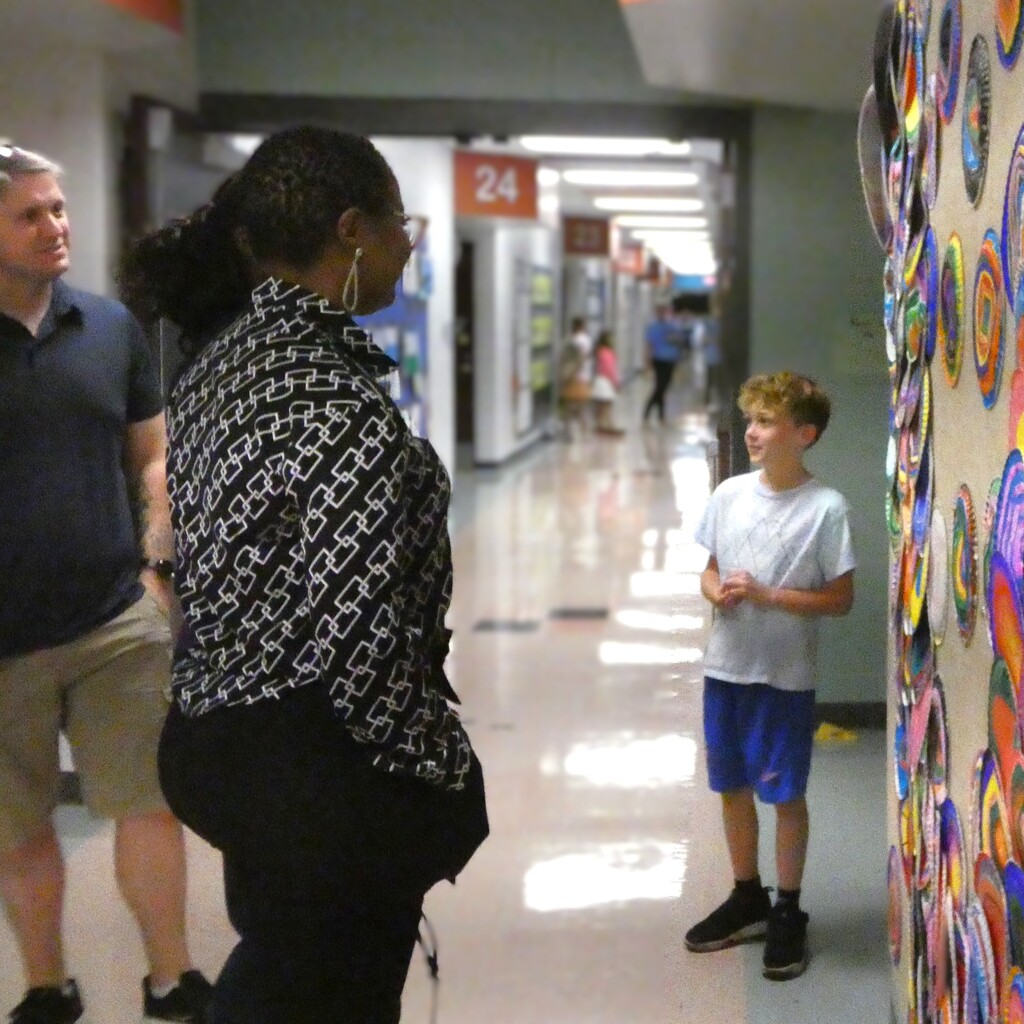Student describes work of school-wide art project to guests
