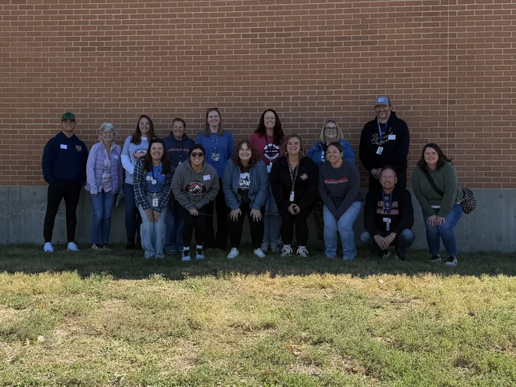 a bunch of staff standing against a brick wal
