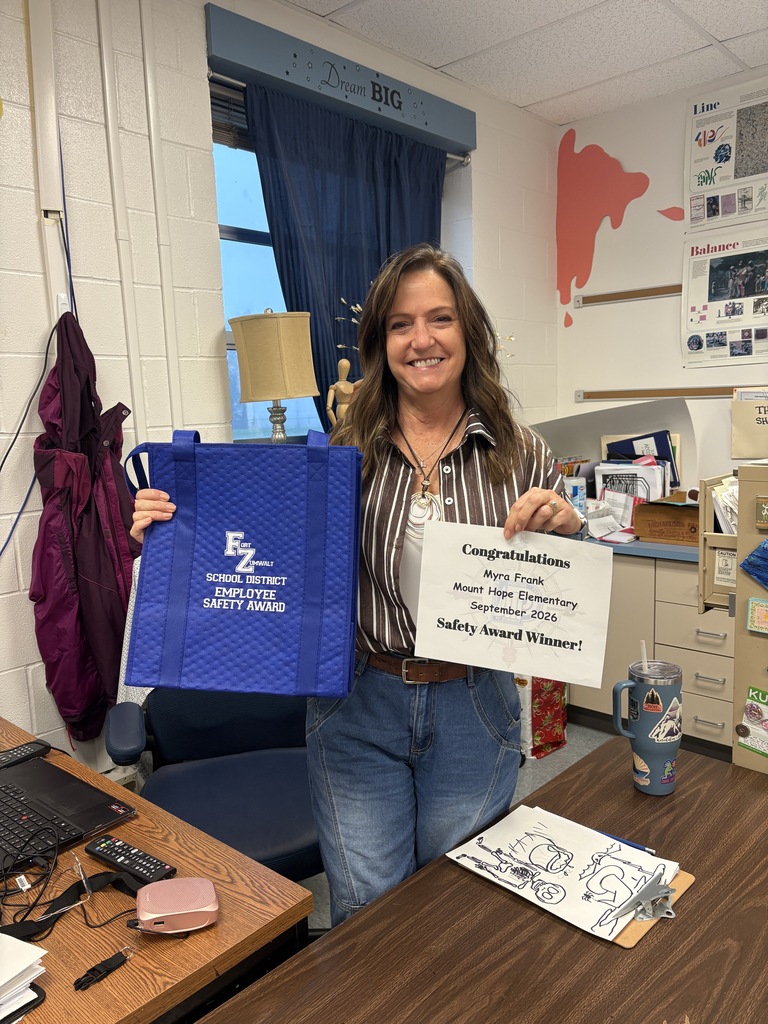 Teacher standing in classroom with award.