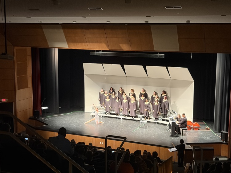 Karis Aubuchon performing a dance on stage while choir sings