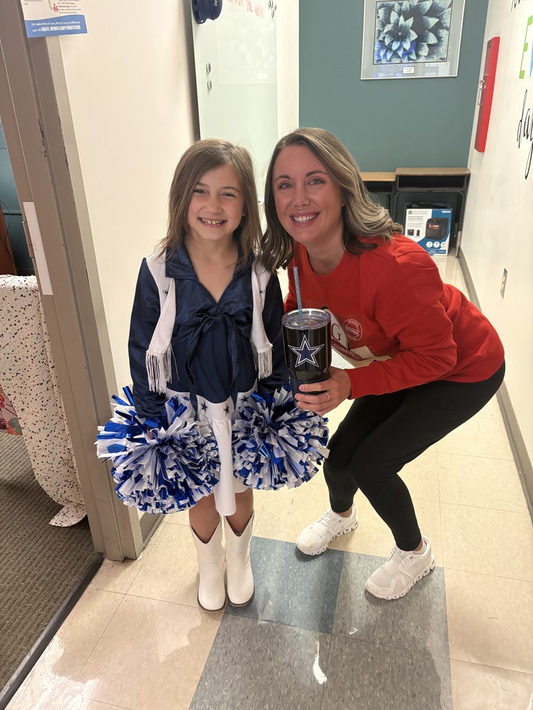 A student dressed as a Dallas Cowboys cheerleader standing next to her principal.
