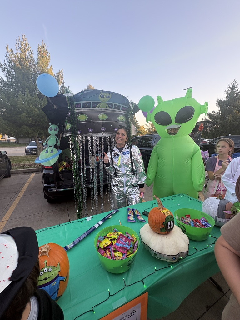 Students and parents handing out candy at a trunk or treat event.