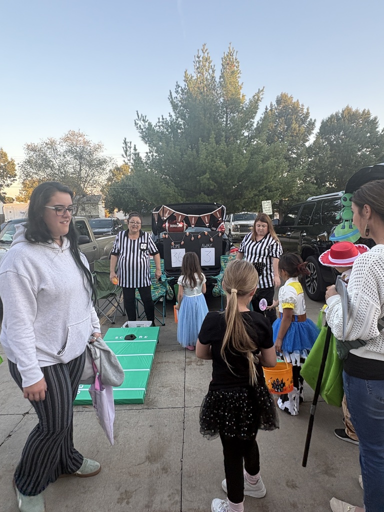 Students and parents handing out candy at a trunk or treat event.