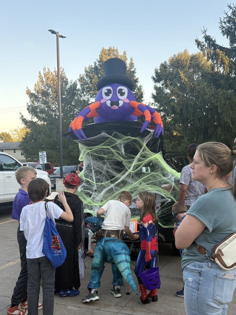 Students and parents handing out candy at a trunk or treat event.