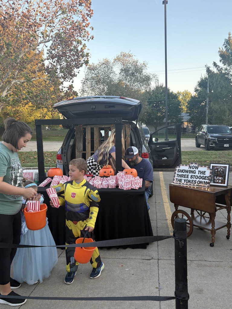 Students and parents handing out candy at a trunk or treat event.
