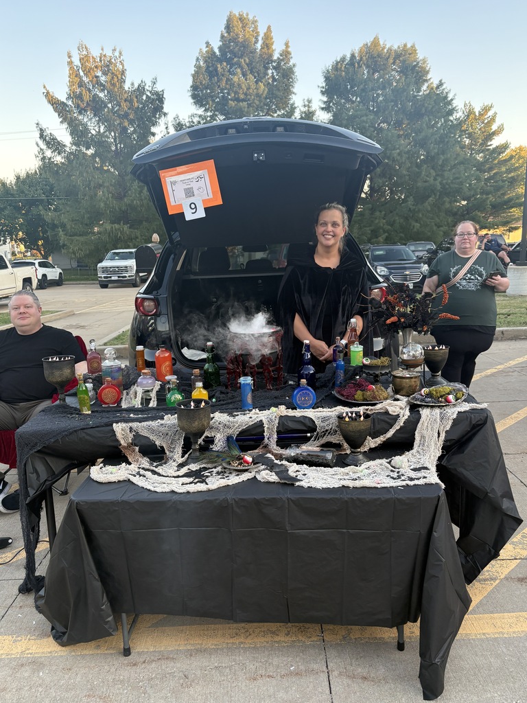 Students and parents handing out candy at a trunk or treat event.
