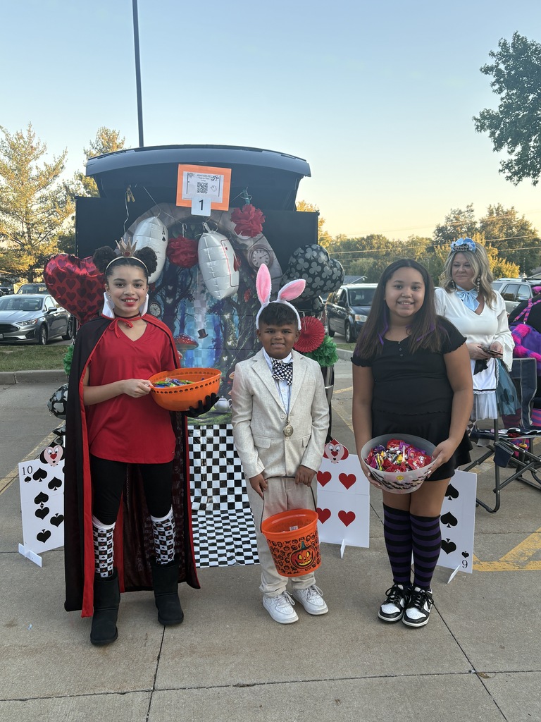Students and parents handing out candy at a trunk or treat event.