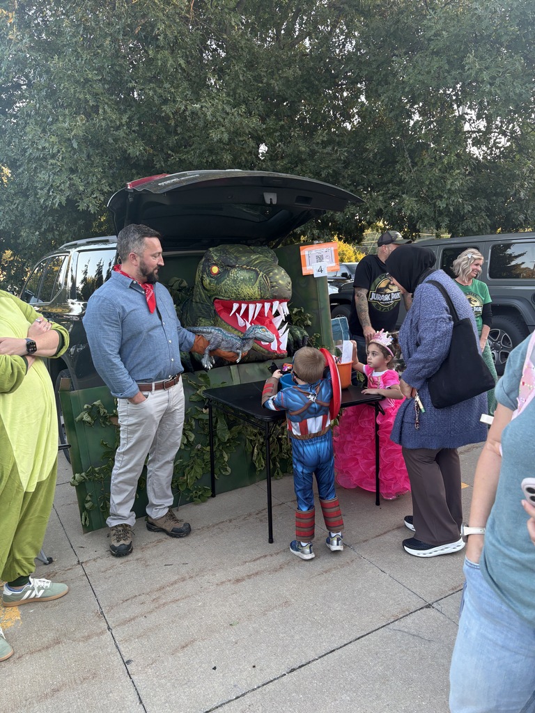 Students and parents handing out candy at a trunk or treat event.