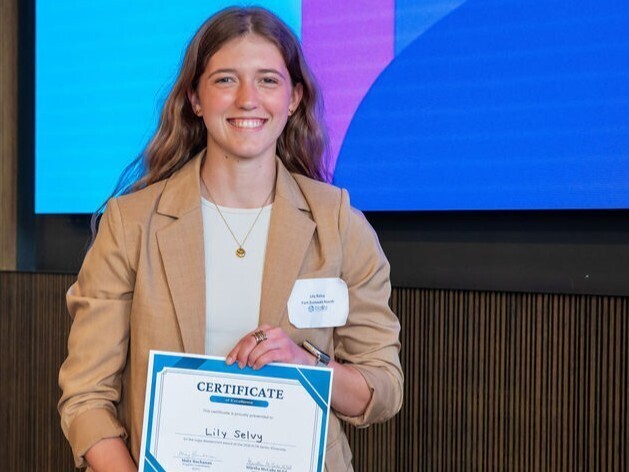 student poses with award