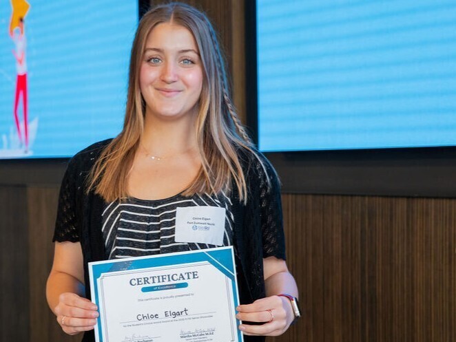 student poses with award