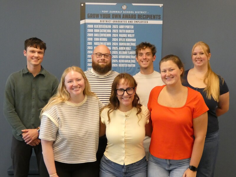 Current Growing Teachers pose in front of honor wall