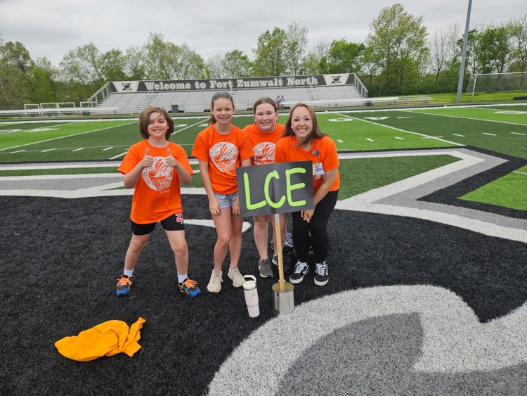 runners in orange on a football field