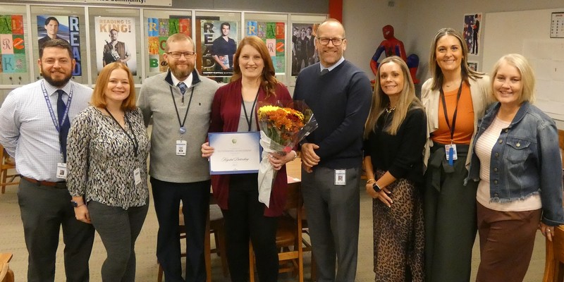 Deterding poses with school and district administrators. She is at center holding certificate and flowers