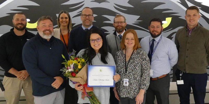 Harting Scoles poses with school and district administrators. She is at center holding certificate and flowers