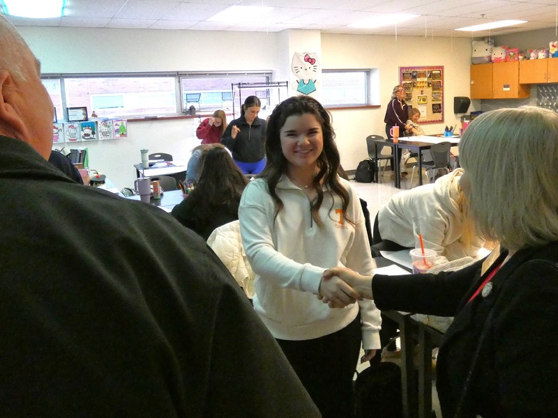 Student shakes hands with legislators, welcoming them to the Biomedical Classroom