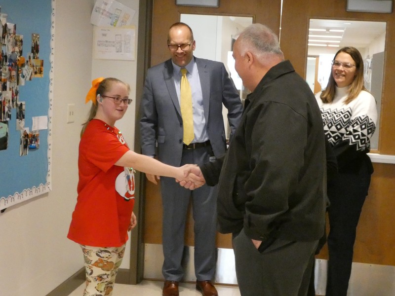 Student shakes hands with legislator as school leaders smile