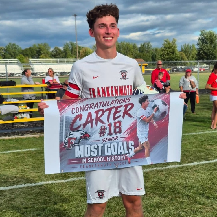 soccer athlete Carter Stapleton holds a banner announcing his record of most goals in school history