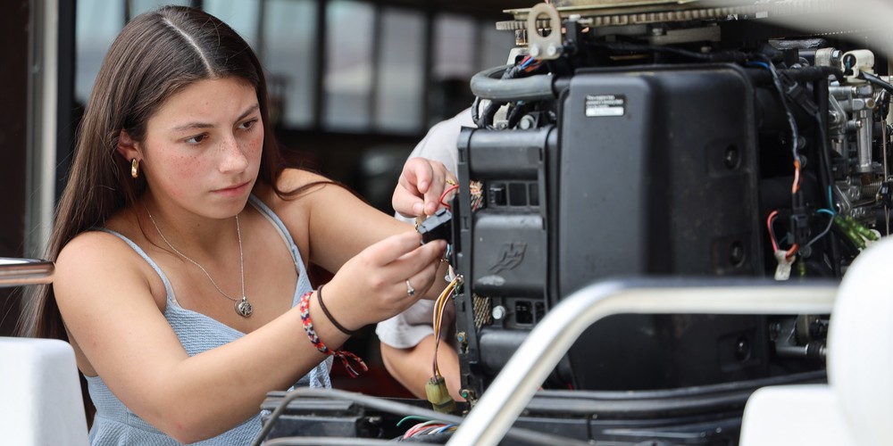 Marine Tech student plugs cables on engine