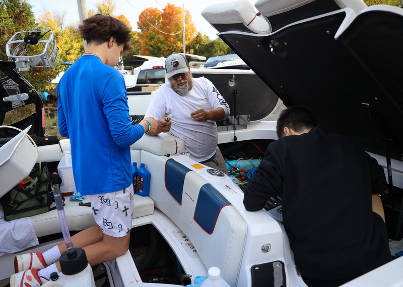 Marine Technology students and a Fogarty's Lake Flower Marina employee work on a large internal boat engine.