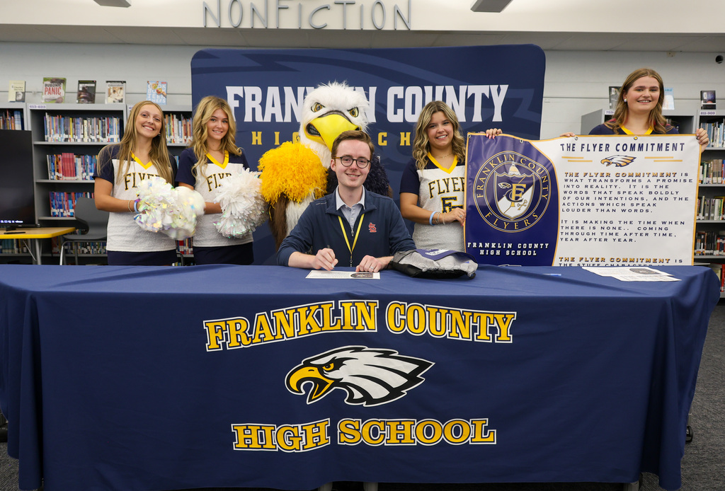 New teacher smiles with FCHS cheer squad after signing the Flyer Commitment.