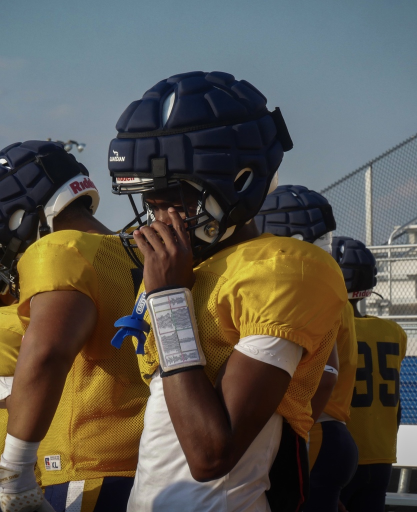 Flyer football players holds helmet on the sideline.
