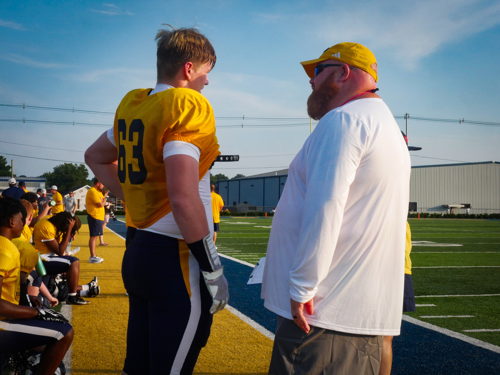 Football player talks to coach on the sideline.