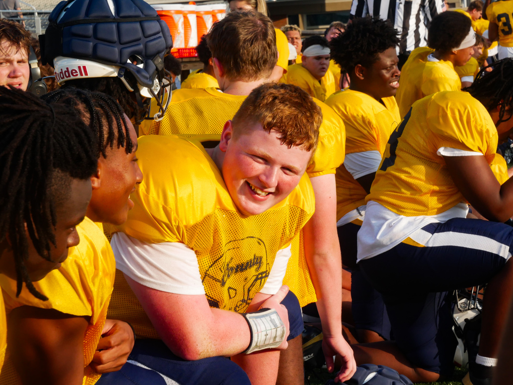 Flyer football players smiles at the camera on the sideline.