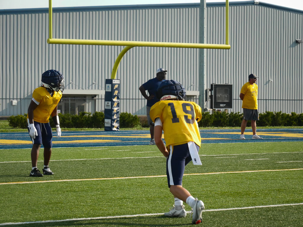 Football players practice on the field.