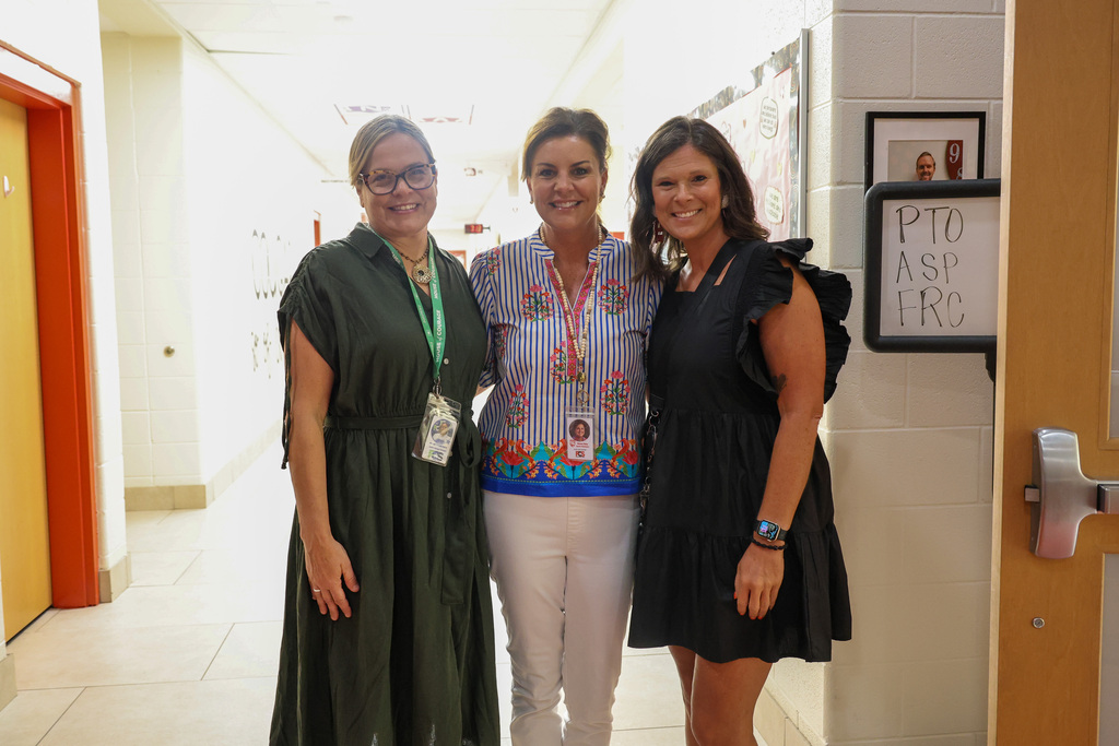 Three Collins Lane Elementary staff members pose for a photo in the hallway.