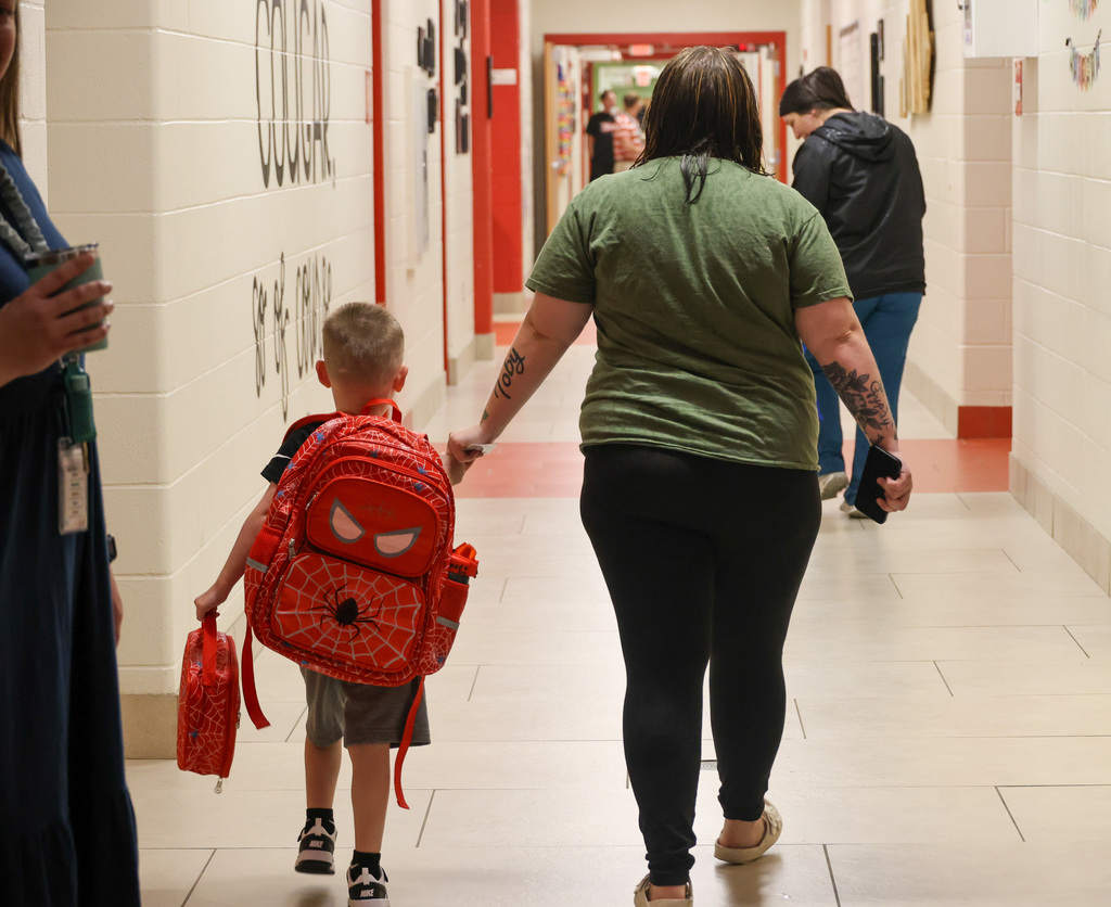 Student walks with parent into Collins Lane Elementary on the first day of school.