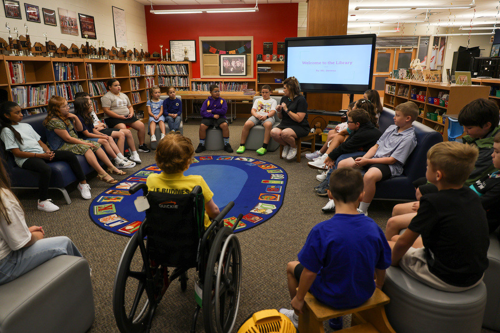 Collins Lane Elementary Librarian speaks to students sitting in a circle. 