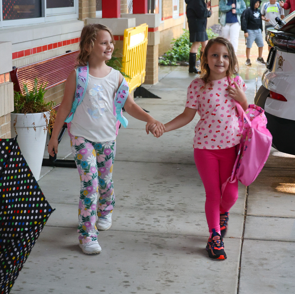 Two students hold hands as they enter Collins Lane Elementary on the first day of school.