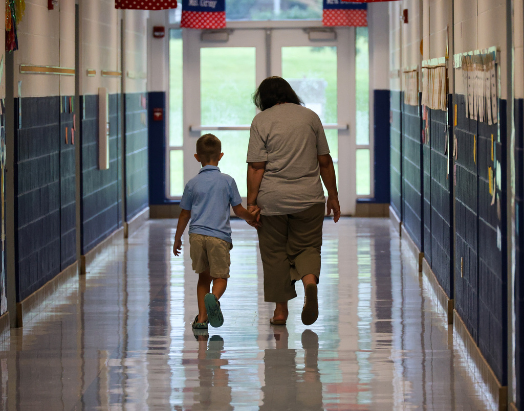 Student and staff hold hands walking down the hall.