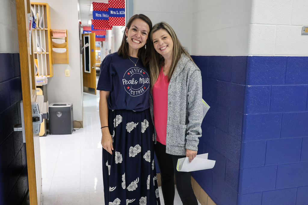 Peaks Mill Elementary teachers smile for a photo in the hallway.