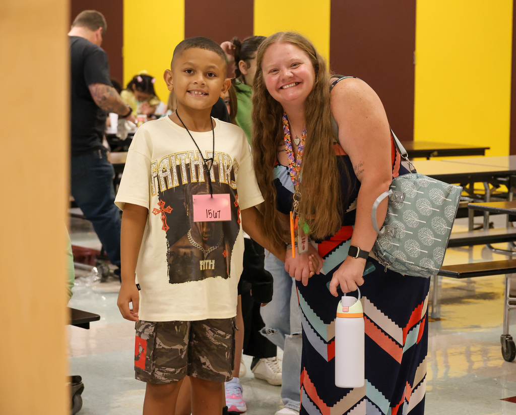 A student and teacher hold hands in the cafeteria at Elkhorn Elementary School.