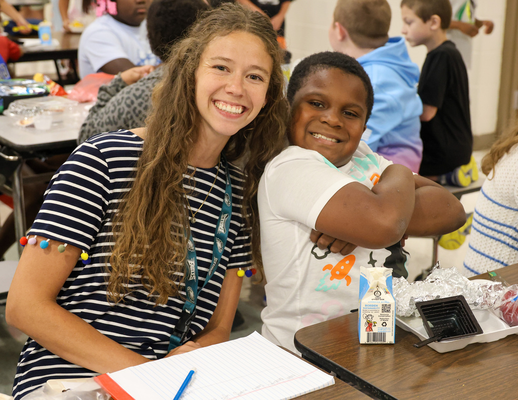 Elkhorn Elementary School teacher and student smile at the camera in the cafeteria.