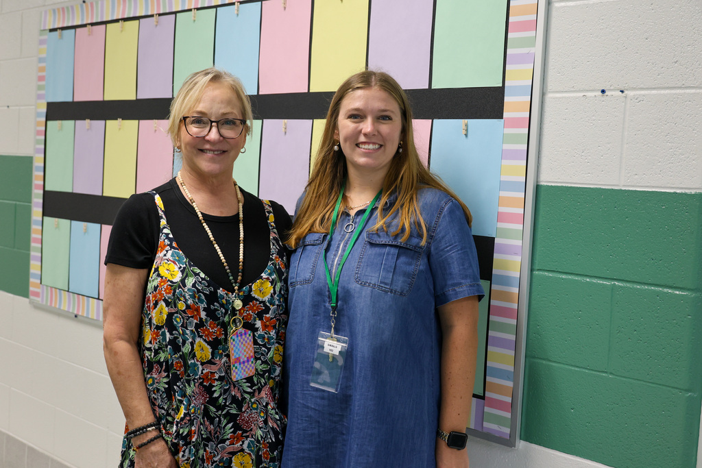 Bridgeport Elementary teachers smile in the hallway next to a bulletin board.