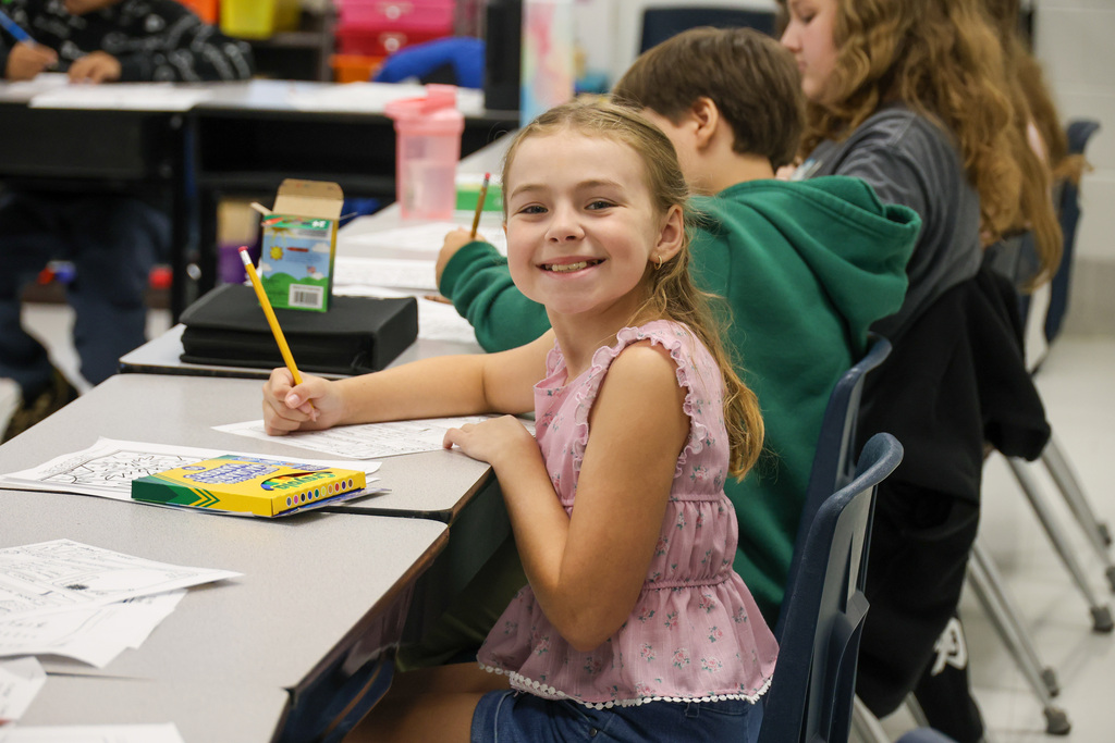 Bridgeport Elementary student smiles with a pencil in her hand and sitting at her desk.