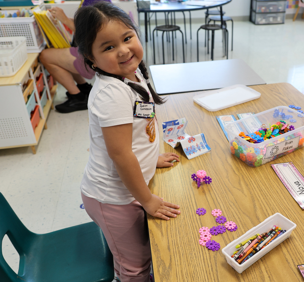 ELV student stands at desk smiling.