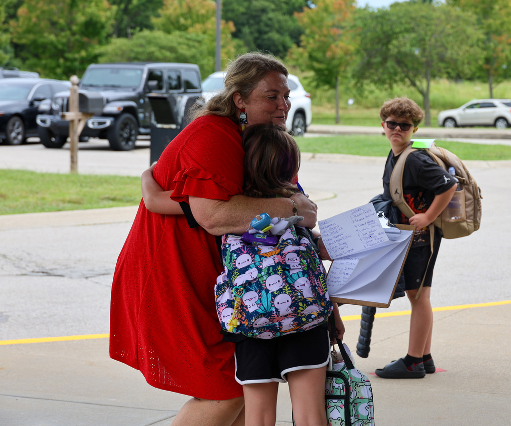 Hearn staff member hugs student outside of the school during drop off.