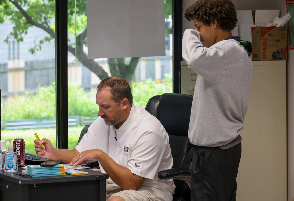 A student receives homework help from a teacher at his desk.
