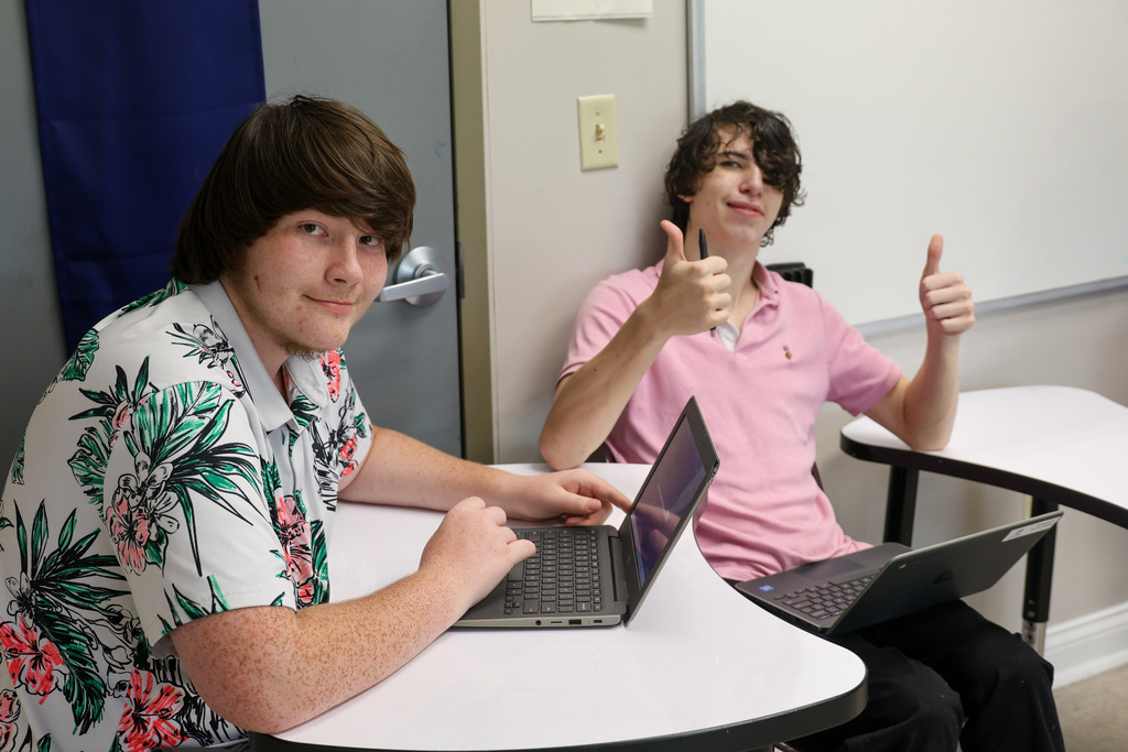 Two students at the Academy smile for a photo. The student on the right has two thumbs up.