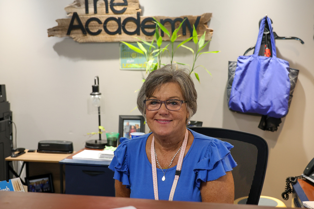 The Academy Secretary, Jerri, smiles for a photo at her desk.