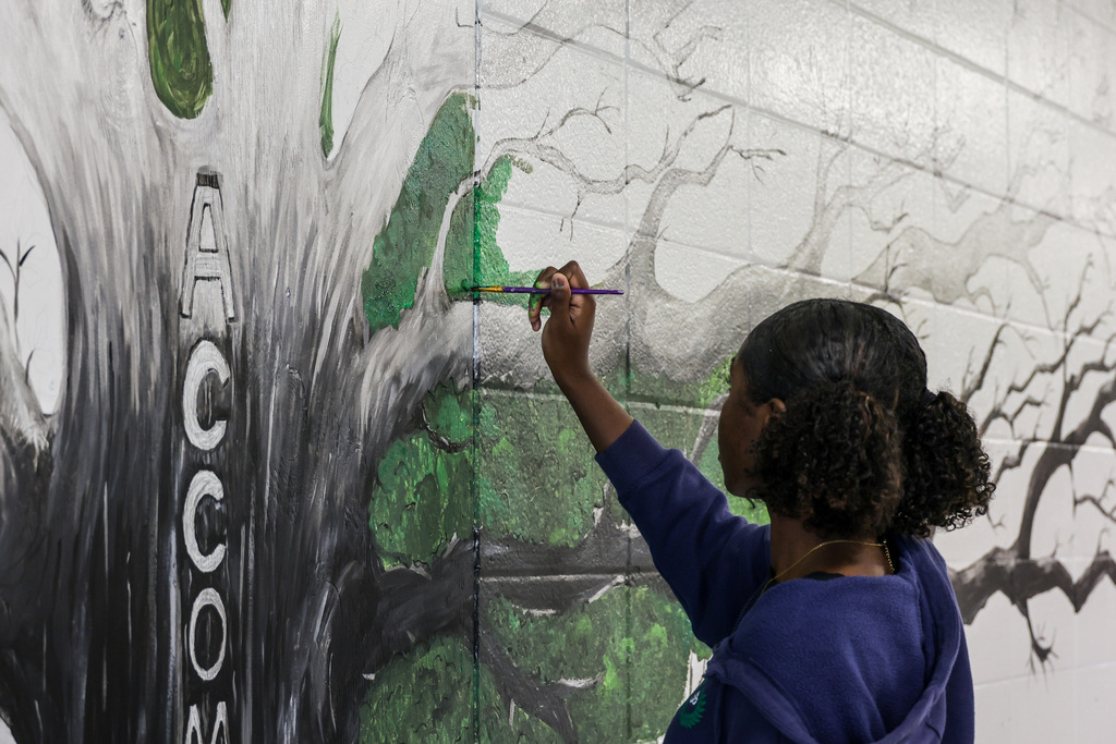 WHHS Senior Kendria Wickers paints mural "We are Hills" mural in the hallway.