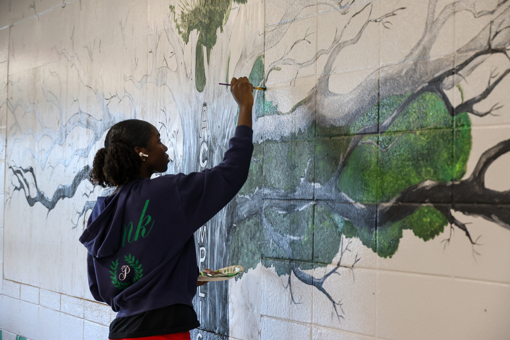 WHHS Senior Kendria Wickers paints mural "We are Hills" mural in the hallway.