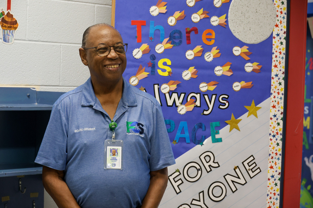 Board member Chuck Fletcher stands in the doorway of a preschool classroom smiling.